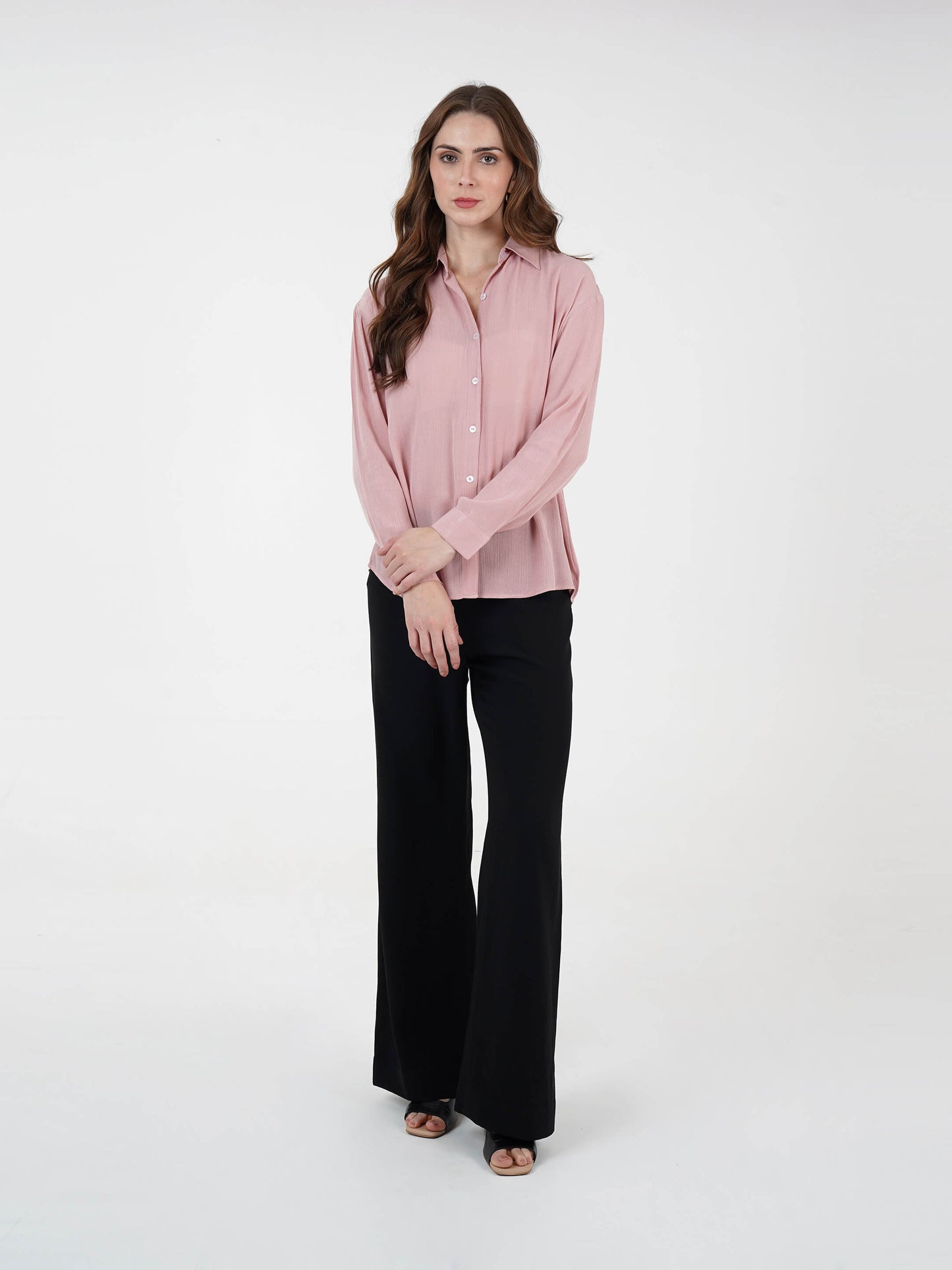 Woman wearing a pink blouse and black pants on a white background
