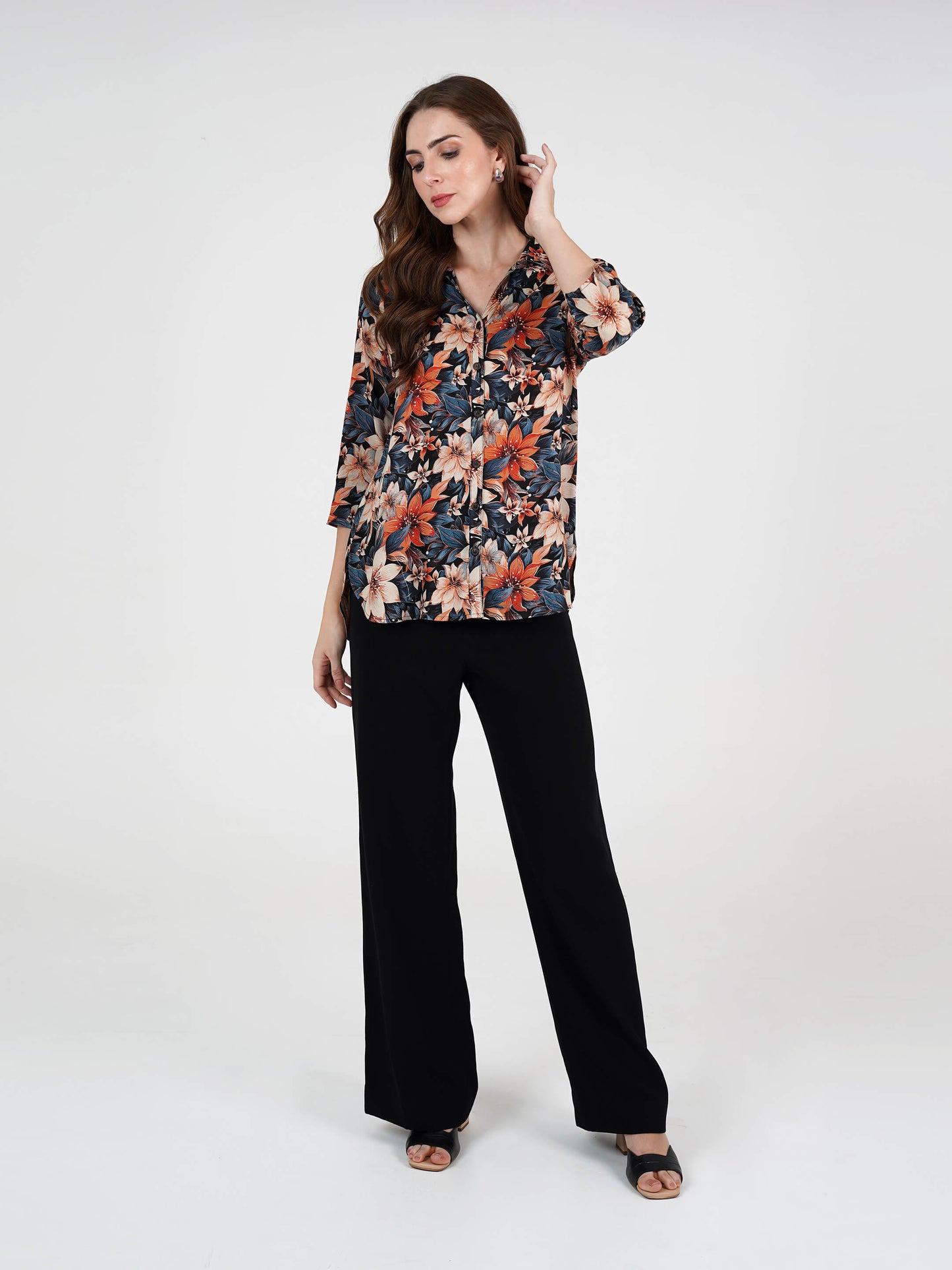 Woman wearing a floral blouse and black pants on a white background